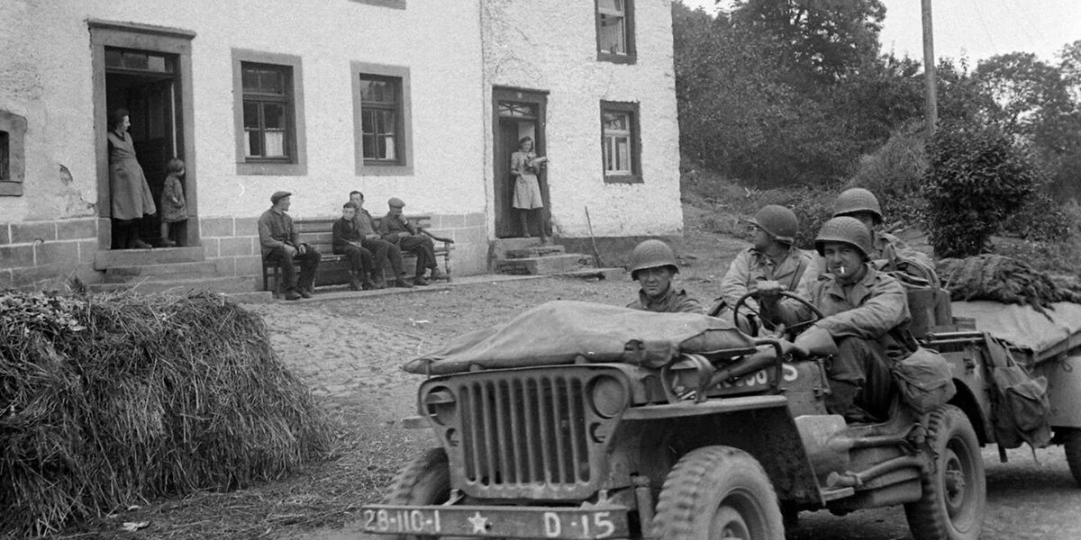 Een amerikaneschen Jeep fiert duerch een Duerf. | © LM Archives - Ralph Morse