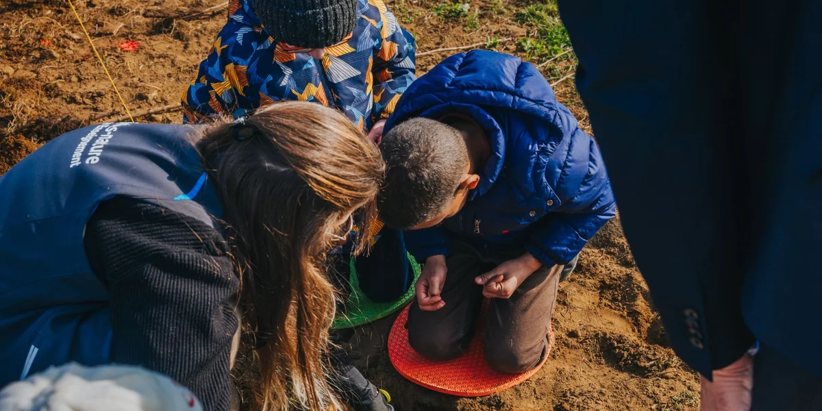 Déi kleng Hobbygäertner, mat Gummisstiwwel a Schëpp ekipéiert, hëllefen d’Sträicher anzeplanzen | © Mick Drulang/VDL